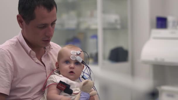 お父さんの手に医療用センサーで赤ちゃんを保持しています。 — ストック動画