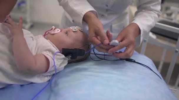 Niño con un chupete en la boca y sensores médicos en la cabeza — Vídeos de Stock