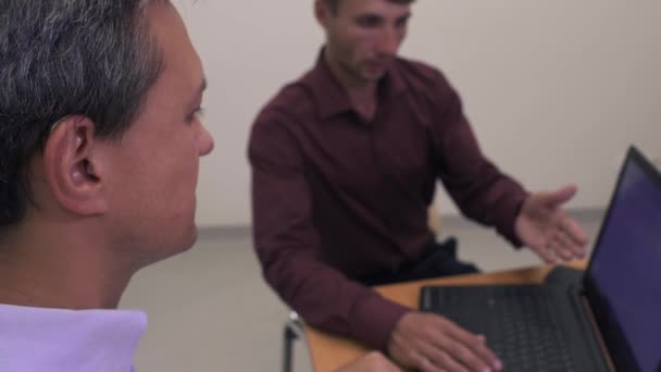 Twee knappe mannen op een tafel voor een laptop — Stockvideo