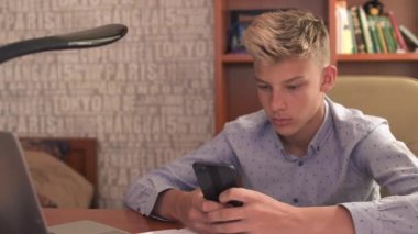 Genç adam dizüstü bilgisayar ve cep telefonu üzerinde tıklayarak