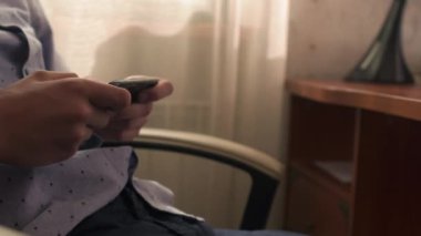 Çocuk bir sandalyede oturuyor ve telefonda tıklayarak