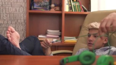 Genç adam çıplak ayaklı deri sandalyede oturur