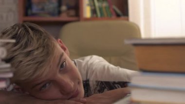 İki kitap yığınları masada yatıyor. Çocuk defterler ayrı iter ve kameraya benziyor. Genç odasında okuyor