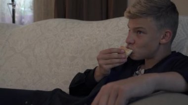 Genç adam koltuk döşeme pizza yiyor