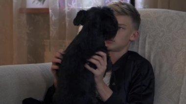 Genç adam kanepede oturan ve köpek okşayarak.