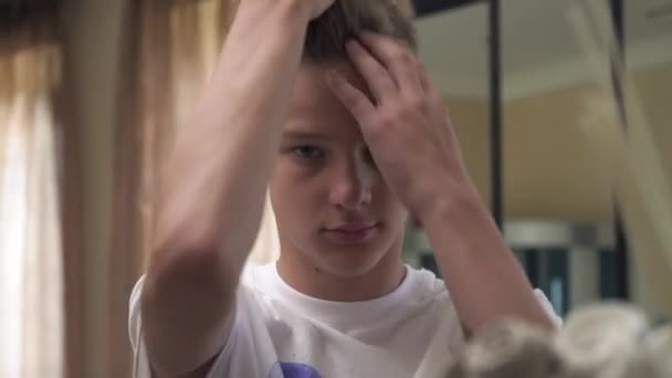 O menino penteia o cabelo na cabeça com os dedos — Vídeo de Stock