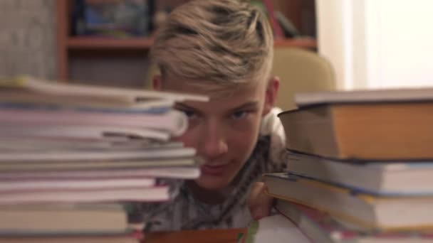 Jeune garçon pousse les livres à part et regarde la caméra — Video