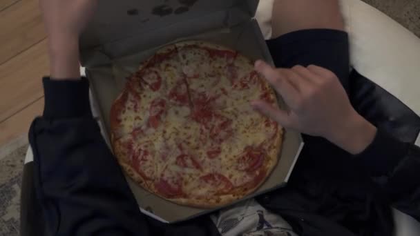 Мальчик ест пиццу в современной комнате — стоковое видео