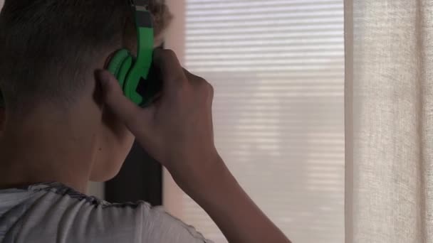 Мальчик слушает музыку у окна — стоковое видео