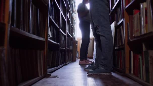 Besucher der Bibliothek stehen in Reihen mit Büchern. — Stockvideo