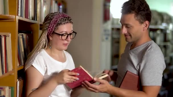 Chlap a dívka se mluví v knihovně — Stock video