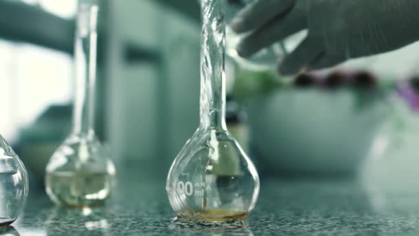 Laboratorieassistent häller vattnet i kolven — Stockvideo