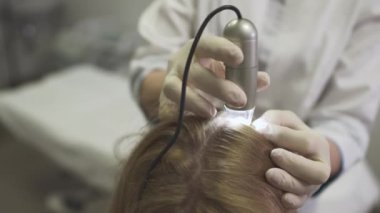 Dermatolog kızın kafasına cilt inceliyor