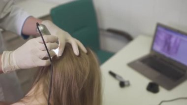 Dermatolog kızın kafasına cilt inceliyor