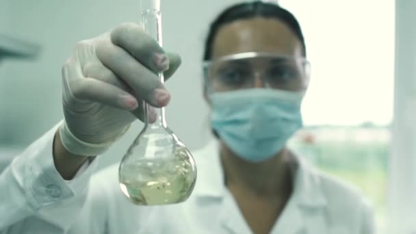 Asistente de laboratorio chica agita el líquido en un frasco — Vídeo de stock