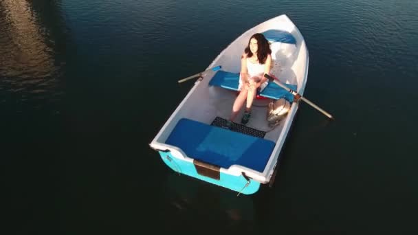Chica se sienta en un barco y abraza sus rodillas — Vídeos de Stock