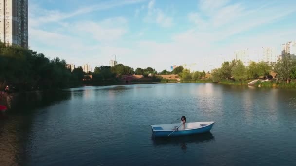 Hermosa chica se sienta en un barco en el lago — Vídeo de stock