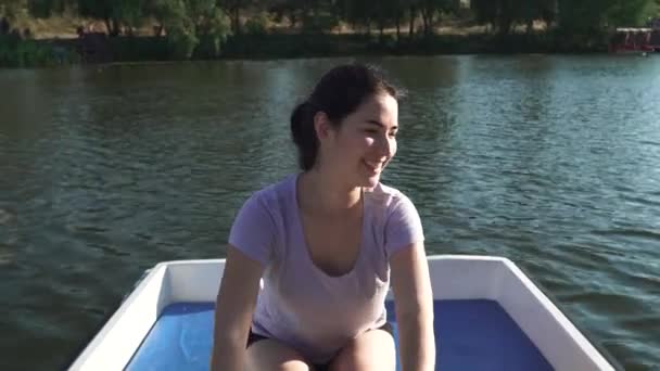 Όμορφο κορίτσι που γελάει και λειτουργεί κουπιά σε μια βάρκα — Αρχείο Βίντεο