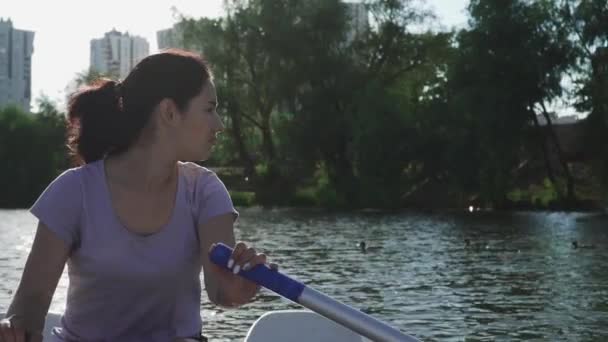 Hermosa chica remando en un barco en un lago — Vídeo de stock