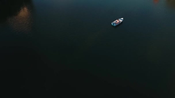Jovem está sentado em um barco no lago — Vídeo de Stock