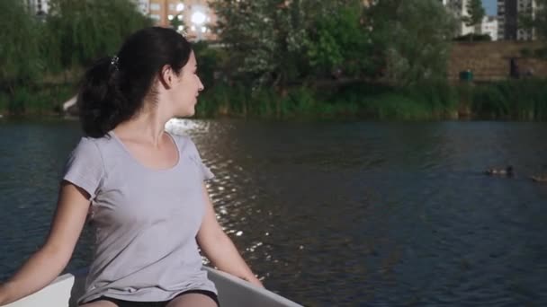 Hermosa joven está sentada en un barco — Vídeo de stock