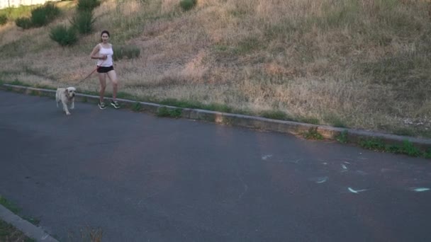 Jeune fille courir avec un chien à l'extérieur — Video