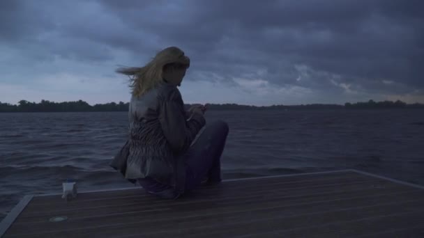 Mooi meisje zit op de rand van de pier — Stockvideo