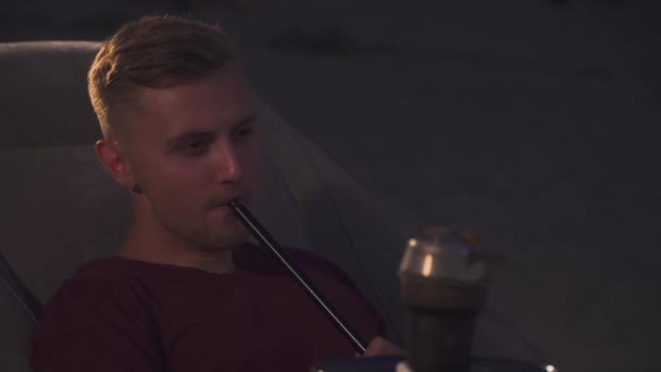 年轻男子坐在椅子上享受水烟 — 图库视频影像