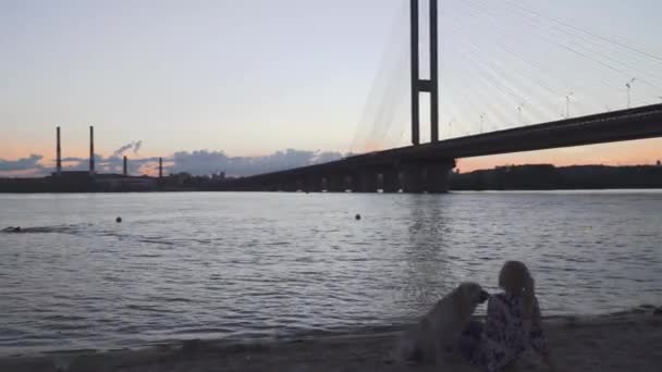 美丽的女孩坐在河岸边的狗 — 图库视频影像