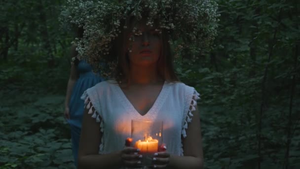 Krásná dívka drží hořící svíčku v lese