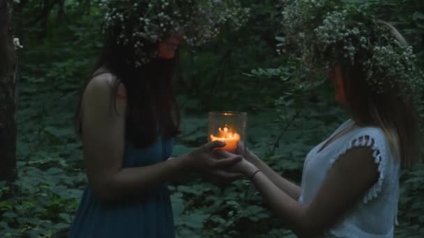 Dos chicas jóvenes sostienen una vela encendida en el bosque — Vídeos de Stock