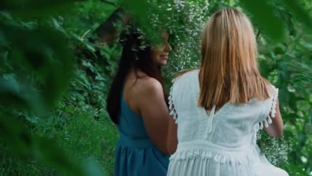 Two beautiful girls in long dresses are sitting in the woods — Stock Video