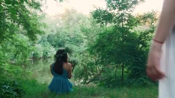 Krásná dívka sedí u jezera v lese — Stock video