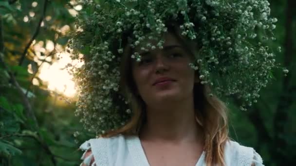 Menina bonita com uma coroa de flores no parque — Vídeo de Stock