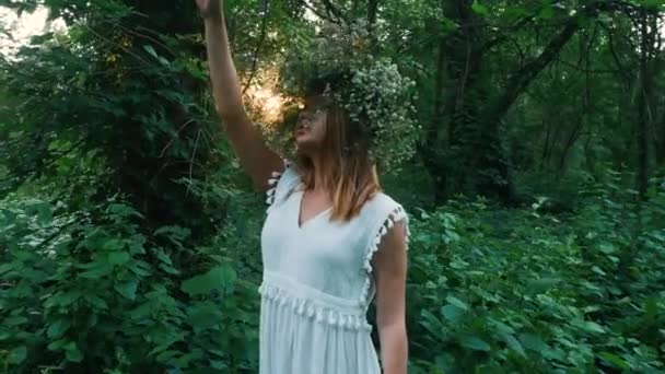 Menina bonita com uma coroa de flores no parque — Vídeo de Stock