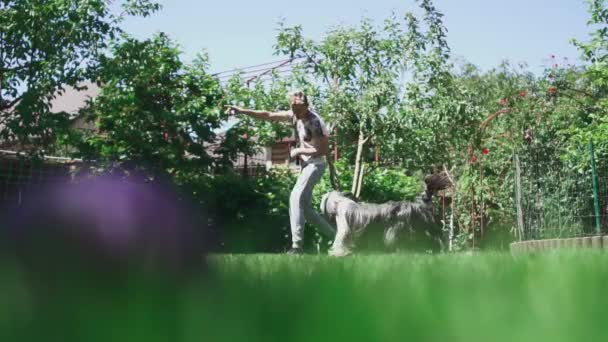 Хлопчик кидає собаку їжу і тварина ловить її — стокове відео