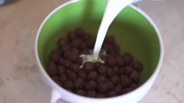 Adición de leche al cereal en tazón amarillo en la cocina — Vídeos de Stock