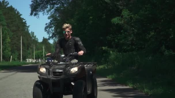 Joven conducir en la bici cuádruple en una carretera rural — Vídeo de stock