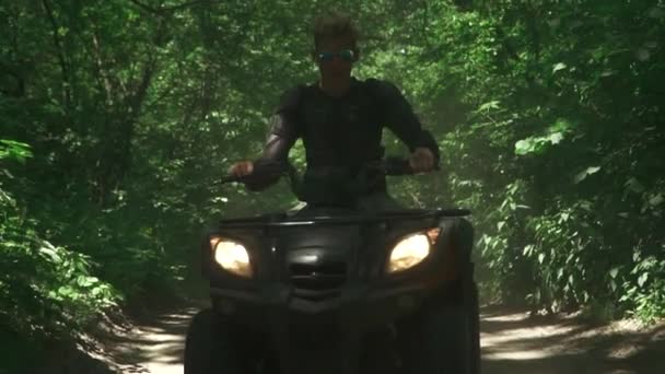 Молодой человек водит квадроцикл в лесу — стоковое видео