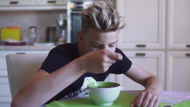 Blond boy eats breakfast at the kitcken — Stock Video