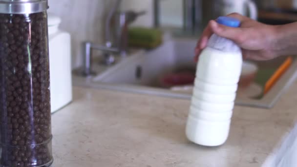Мужчина открывает бутылку молока на кухне — стоковое видео