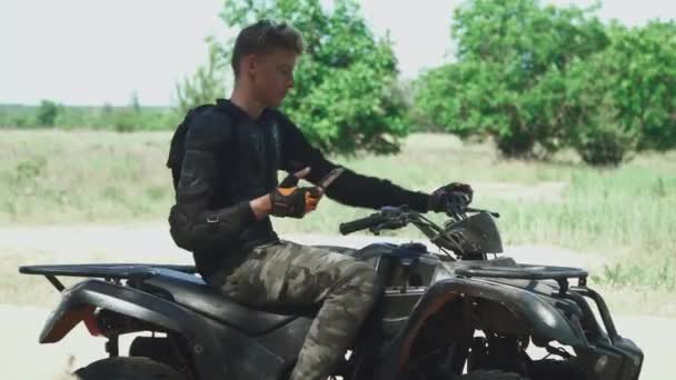 Jongeman is op Atv en clicing leggen van zijn mobiele telefoon — Stockvideo