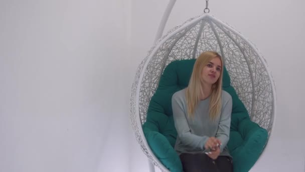 Beautiful girl swinging in a pendant chair — Stock Video