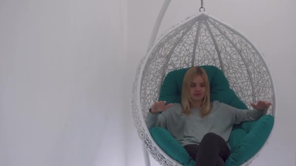Beautiful girl swinging in a pendant chair — Stock Video