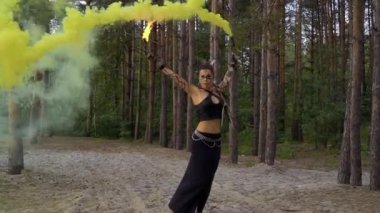 Vahşi görünümlü kadın ateş sopa ve duman bombası ile dans ediyor