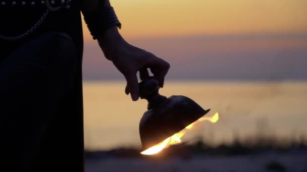 Ruka ženy otáčí ohněm mísu v západu slunce pozadí — Stock video