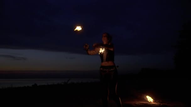 Красивая женщина танцует с огнем у реки ночью — стоковое видео