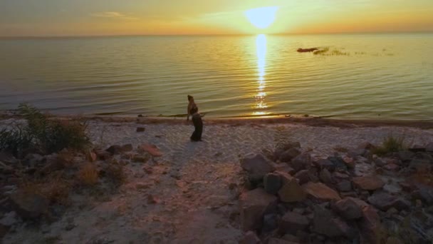 Όμορφη κοπέλα χορεύει με ηλιοβασίλεμα κοντά στο νερό — Αρχείο Βίντεο