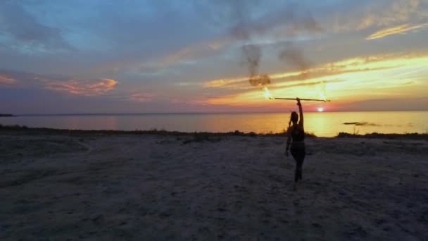 Hermosa mujer está sosteniendo palo de fuego sobre su cabeza en la playa — Vídeos de Stock