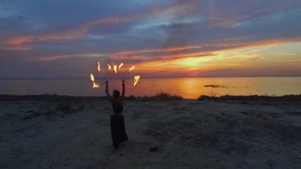 Hermosa mujer camina hacia el río sosteniendo fuego ardiente ventiladores — Vídeo de stock